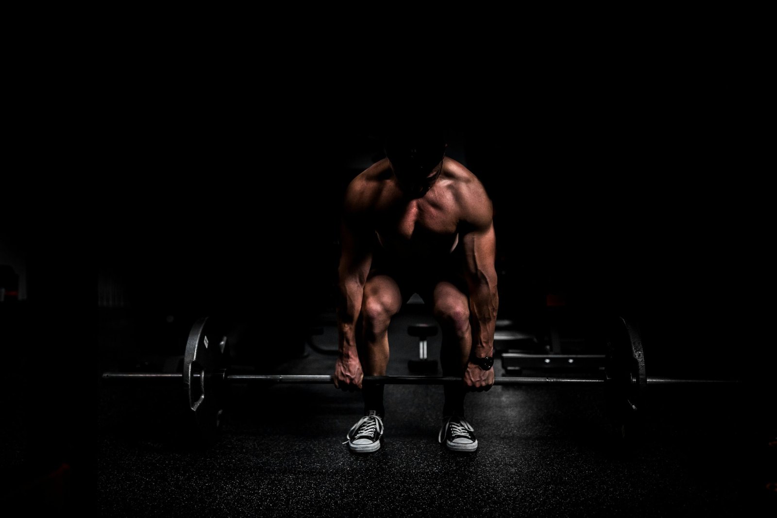 topless man in black shorts sitting on black and silver barbell